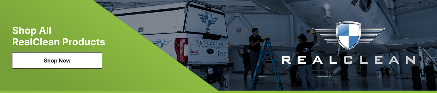 An image of a plane in a hangar being cleaned by a group of aircraft detailers with the RealClean Aviation Products logo on top. The Pilot John International Shop All RealClean Products Shop now button is next to it.
