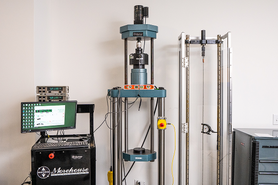 Force calibration machine with computer control system and vertical load frame in a testing lab.