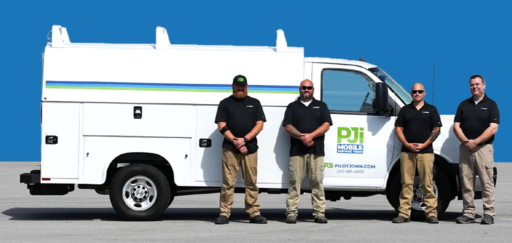 Four PJi Mobile Service Team technicians stand in front of a branded white service van, wearing black shirts and khaki pants, posing for a team photo against a blue background.