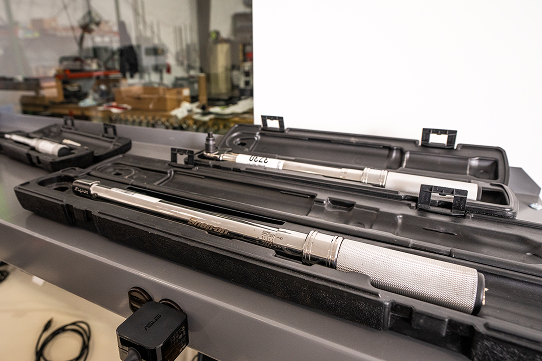 Torque wrenches in protective cases arranged on a workbench inside a calibration lab.