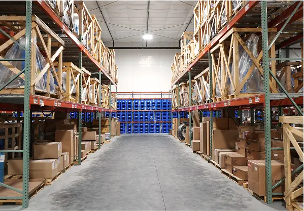 Warehouse aisle with tall shelving racks filled with aviation parts, crates, and inventory organized for storage.