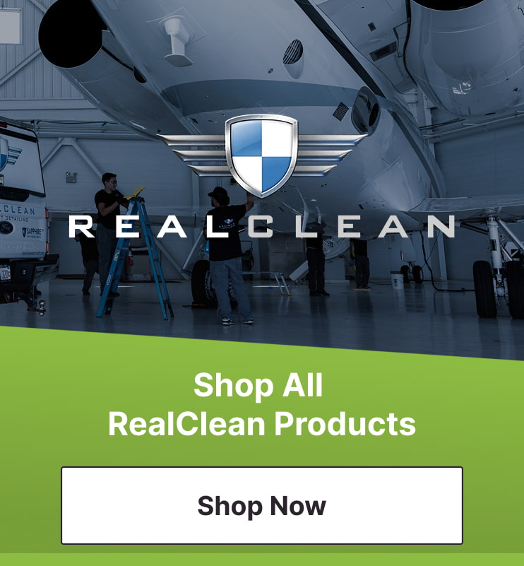 An image of a plane in a hangar being cleaned by a group of aircraft detailers with the RealClean Aviation Products logo on top. The Pilot John International Shop All RealClean Products Shop now button is next to it.